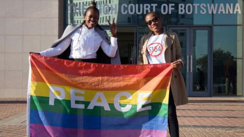 Activists pose with a rainbow flag as they celebrate outside Botswana High Court in Gaborone after the landmark ruling in June