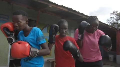 Girls line up wearing boxing gloves