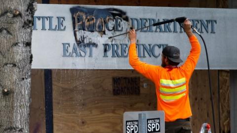 A worker removes graffiti off a police precinct sign