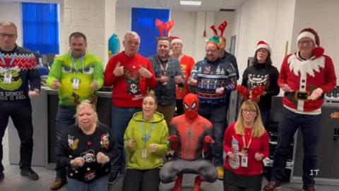 Staff , some in Christmas hats and one dressed as Spiderman, signing in Makaton