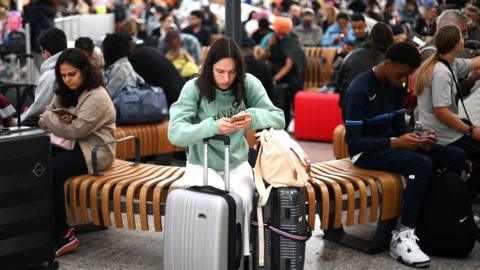 Passengers wait at Stansted Airport, north of London, on 29 August 2023 after UK flights were delayed over a technical issue