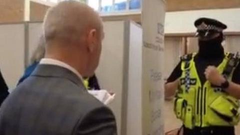 Protestors talking to police at a vaccination centre in Stockport