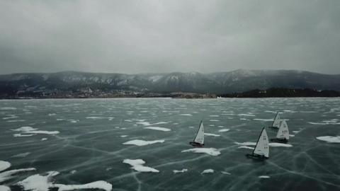 Yachts gliding on frozen lake