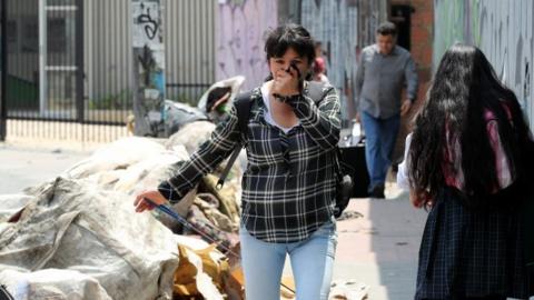 Pedestrians walk by garbage bags in Bogota, Colombia, 07 February 201