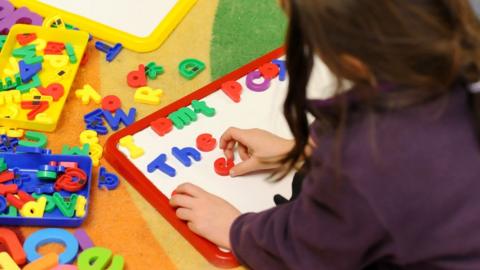 A generic stock photo shows primary school child at work in a classroom