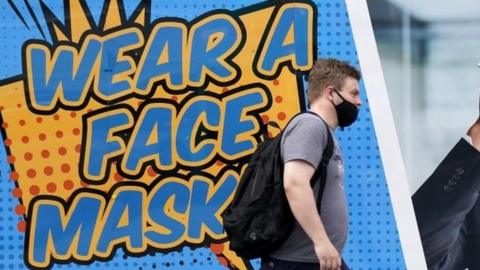 Man in front of 'Wear a face mask' sign