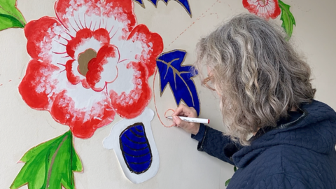 A woman drawing flowers onto a wall