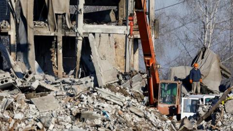 Workers remove debris of a destroyed building