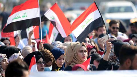 Iraqis wave national flags at a protest in Baghdad on 11 November 2019