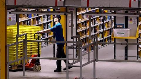 An employee moves stock in an Amazon warehouse