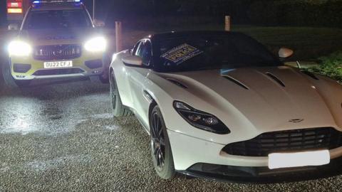 Aston Martin and a police car by the A14 in Cambridgeshire.