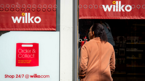 Woman stands in front of Wilko shop