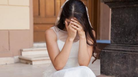 A bride has her hands buried in her face