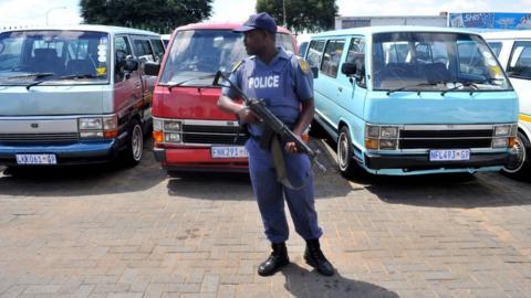 A police officer stands guard at a taxi rank in Soweto