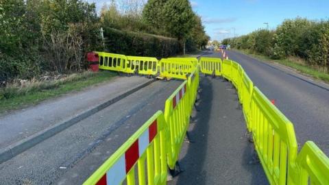 High visibility road barriers and traffic cones cutting the road down to one lane.