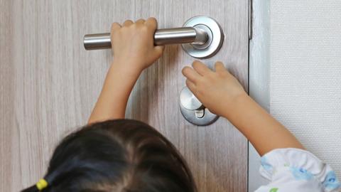 Young child trying to open a heavy door