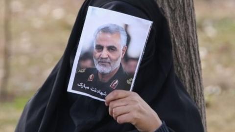 woman covers face with photo of Soleimani, Tehran