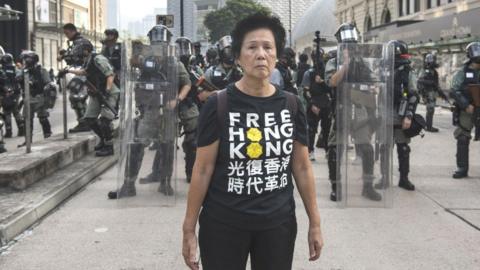 Woman stands in front of police barricade during Hong Kong 2019 pro-democracy protests.
