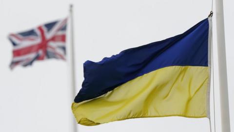 Ukranian flag flying with Union flag in the background
