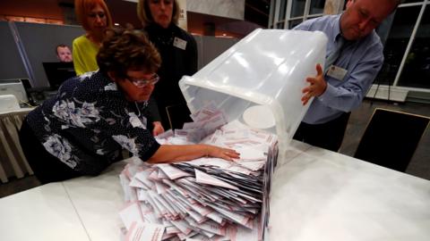 Election officials open ballot boxes during the general election in Riga, Latvia October 6, 2018.