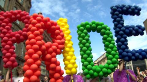 LGBT campaigners march in the Belfast Pride parade, carrying rainbow-coloured balloon display spelling the word PRIDE