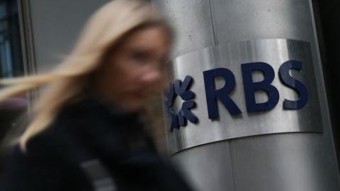 Pedestrian walks past a branch of RBS