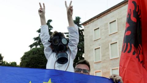 A child wears a gas mask during protests in Tirana