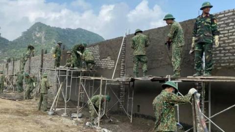 Workers putting up a wall around the airport at Dong Tam, Vietnam