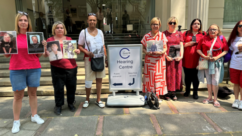 Jane Roche (far left) with others, holding up photos of their loved ones outside of the hearing centre in London