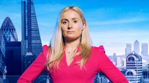 A blonde woman in a pink suit stands in front of a backdrop of London.