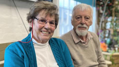 Carol Russell and partner Stephen Leonard Burke sitting side by side smiling