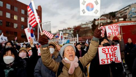 A pro-Yoon protester holds a South Korean flag and an American flag during a rally near impeached South Korean President Yoon Suk Yeol's official residence, after investigators were unable to execute an arrest warrant on Friday for Yeol, according to the Corruption Investigation Office for High-ranking Officials, in Seoul, South Korea, January 3, 2025