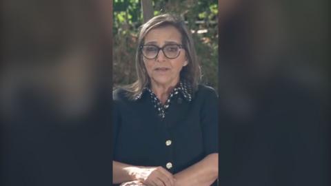 Woman with arms crossed wearing glasses and black top