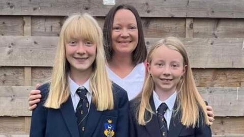 Mum Ruth Inkley is pictured with her two daughters in school uniforms