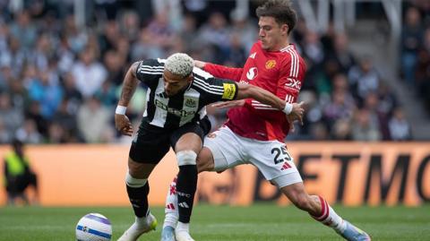 Joelinton of Newcastle United is challenged by Manuel Ugarte of Manchester United