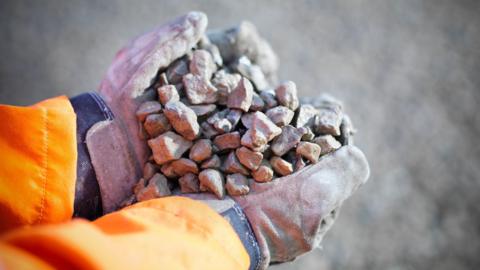 A close up image of a person's hands holding gravel