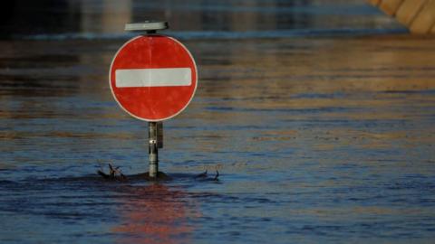 A generic image of flood water partially covering a road sign 