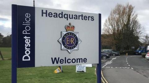 The sign at the entrance to Dorset Police HQ in Winfrith - it bears the force badge and says Dorset Police Headquarters Welcome.