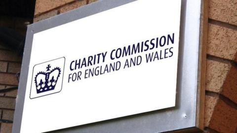A white and blue sign reading "Charity Commission for England and Wales" with a blue crown to the left of it.