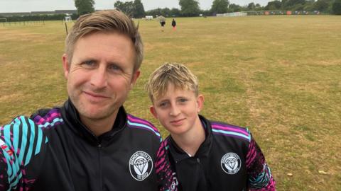 Nick Eyre and his son Ellis smiling at the camera wearing football tops 