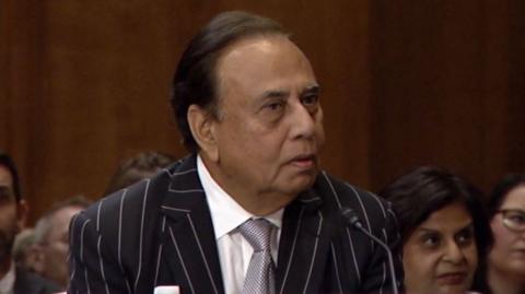 Anjani Sinha is wearing a black and white pinstripe jacket, grey tie and white shirt