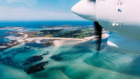 An aeroplane engine and islands with beaches below.