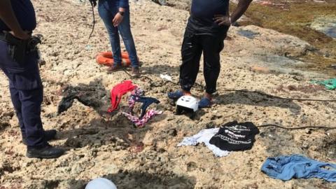 Police officers stand next to clothes recovered from water at the shore where bodies of four people were found, near Willemstad, Curacao January 11, 2018.