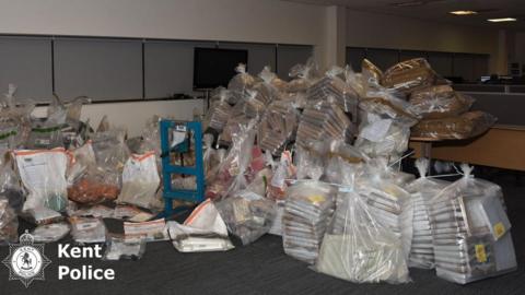 Dozens of large plastic bags containing cannabis pile up in a room