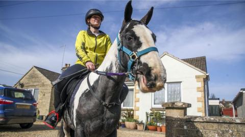 Rescue pony Micky helps owner Abi Eliot-Williams deliver library books to members of the Hullavington Book Group in the village of Hullavington near Malmesbury, Wiltshire.