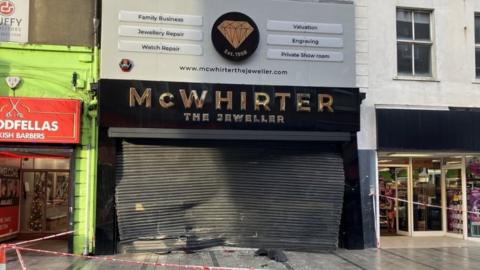 Front of McWhirter's jewellers with damaged shutters