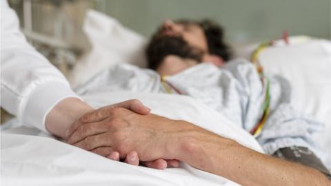 Healthcare staff caring for a patient in hospital bed - stock photo