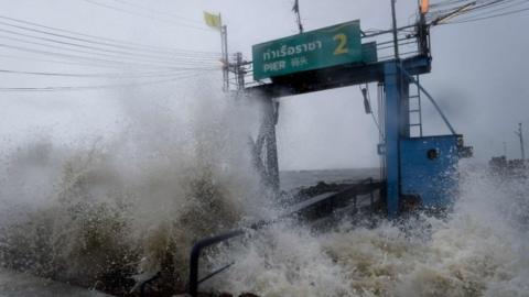 Waves crash into a pier in Thailand during a tropical storm