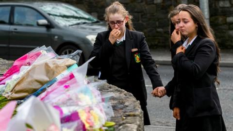 Students from Holy Trinity College leave floral tributes outside The Greenvale Hotel in Cookstown, 19 March 2019