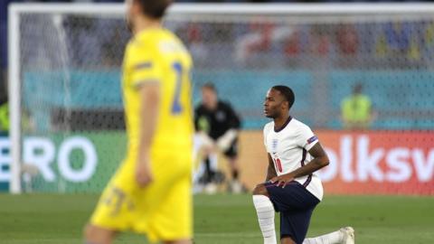 Photograph showing Raheem Sterling taking the knee before a match.